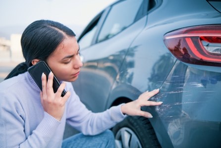 Woman assesses the extent of the accident-damage on a car